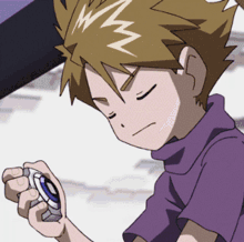 a boy in a purple shirt is holding something in his hands