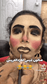 a woman with arabic writing on her face is getting makeup applied