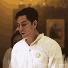 a man in a white shirt has a yellow button on his chest that says " rbd.gif "
