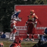 a group of people in superhero costumes are standing in front of a red wall .