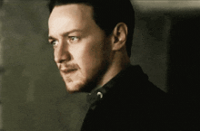 a close up of a man 's face with a beard and a black shirt