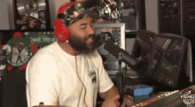 a man wearing headphones is singing into a microphone in front of a sign that says one tribe