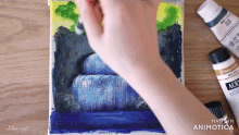 a person is painting a waterfall with a brush and a bottle of acrylic paint