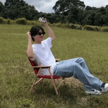 a man sitting in a chair in a field holding a can of soda