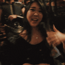 a woman with a ring on her finger smiles in front of a group of people