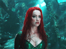 a woman with red hair and a green top is standing in the water