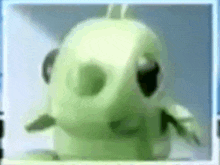 a close up of a green stuffed animal 's face