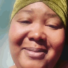 a close up of a woman 's face wearing a turban and smiling