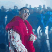a man wearing sunglasses and a red jacket that says ' supreme ' on the front