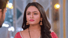 a close up of a woman wearing earrings and a red bindi