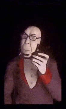 a man with glasses is talking on a cell phone in a dark room .