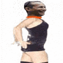 a man in a black tank top and orange choker is dancing with his hands on his hips .