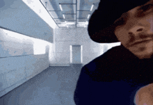 a man in a black hat is standing in an empty room