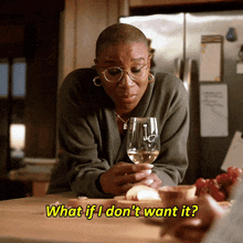 a woman sitting at a table with a glass of wine and the words " what if i don 't want it " above her