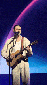 a man is playing a guitar and singing into a microphone
