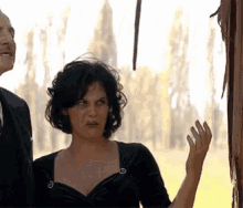 a man and a woman are standing next to each other in a field . the woman is making a funny face .