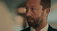 a man with a beard is wearing a suit and a white shirt