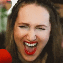 a woman with red lips is smiling with her eyes closed and her tongue out .