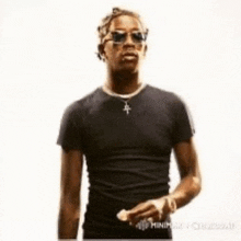 a man wearing sunglasses and a black t-shirt is holding a piece of paper .