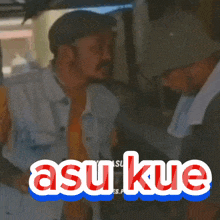 a man with a towel around his neck is talking to another man with the words asu kue on the bottom right
