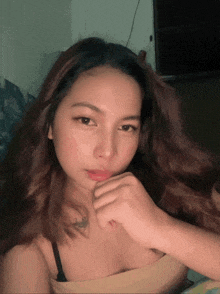 a woman with long hair and a tattoo on her neck looks at the camera