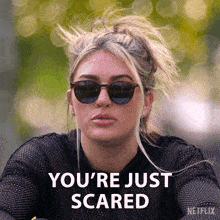 a woman wearing sunglasses says " you 're just scared " in white letters