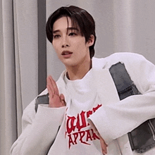 a man wearing a white jacket and a white shirt that says appear on it