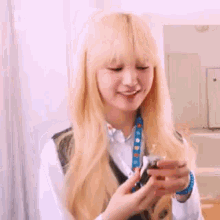 a woman with long blonde hair is holding a small object in her hand .