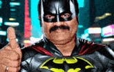 a man wearing a batman costume is giving a thumbs up