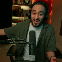 a man wearing headphones is sitting in front of a microphone and smiling