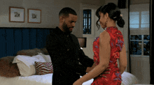 a man and a woman are standing next to each other on a bed
