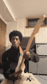 a man is playing a guitar in a room with a bag that says ' x ' on it