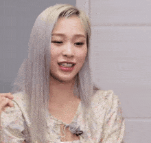 a woman with blonde hair is smiling and holding her hair in front of a sign that says " 남편 ~ 사랑해 "