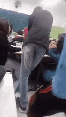 a group of people are sitting at tables in a classroom and one of them has a heart on his back