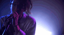 a man singing into a microphone with purple and blue lights behind him