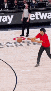 a man in a red shirt is holding a basketball on a basketball court in front of a sign that says way