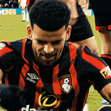 a soccer player wears a red and black jersey with umbro on the front