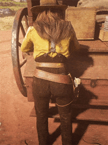 a woman in a yellow shirt and brown pants stands in front of a wooden box