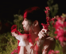 a woman in a white dress holds a red flower