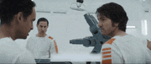 two men in white shirts with orange stripes on the sleeves are standing in front of a machine