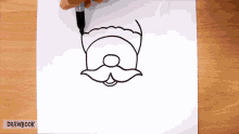a person is drawing a santa claus face with a marker