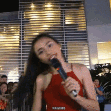 a woman in a red top is singing into a microphone that says hayward on the bottom