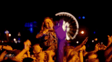 a woman is dancing in front of a crowd at a concert with the word cancella visible
