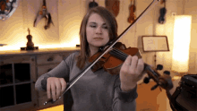 a woman playing a violin in a room with a music stand in the background