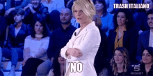 a woman in a white suit is standing in front of a crowd of people and says no .