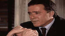 a man in a suit and tie holds a woman 's hands