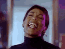 a close up of a woman laughing with her eyes closed and her mouth open .