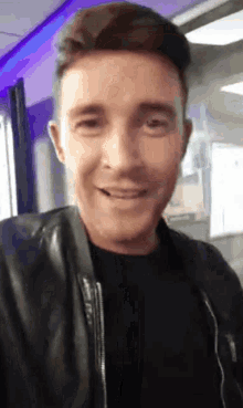 a man wearing a black leather jacket is smiling for the camera .