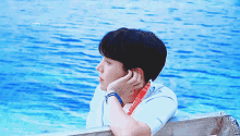 a young man leaning on a wooden railing overlooking the ocean