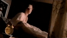 a woman is laying on a bed next to an alarm clock in a room .